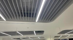 White acoustic baffles suspended from an office ceiling providing sound absorption and visual rhythm.