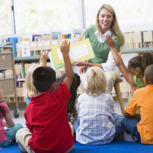 Kindergarten teacher reading to children in library