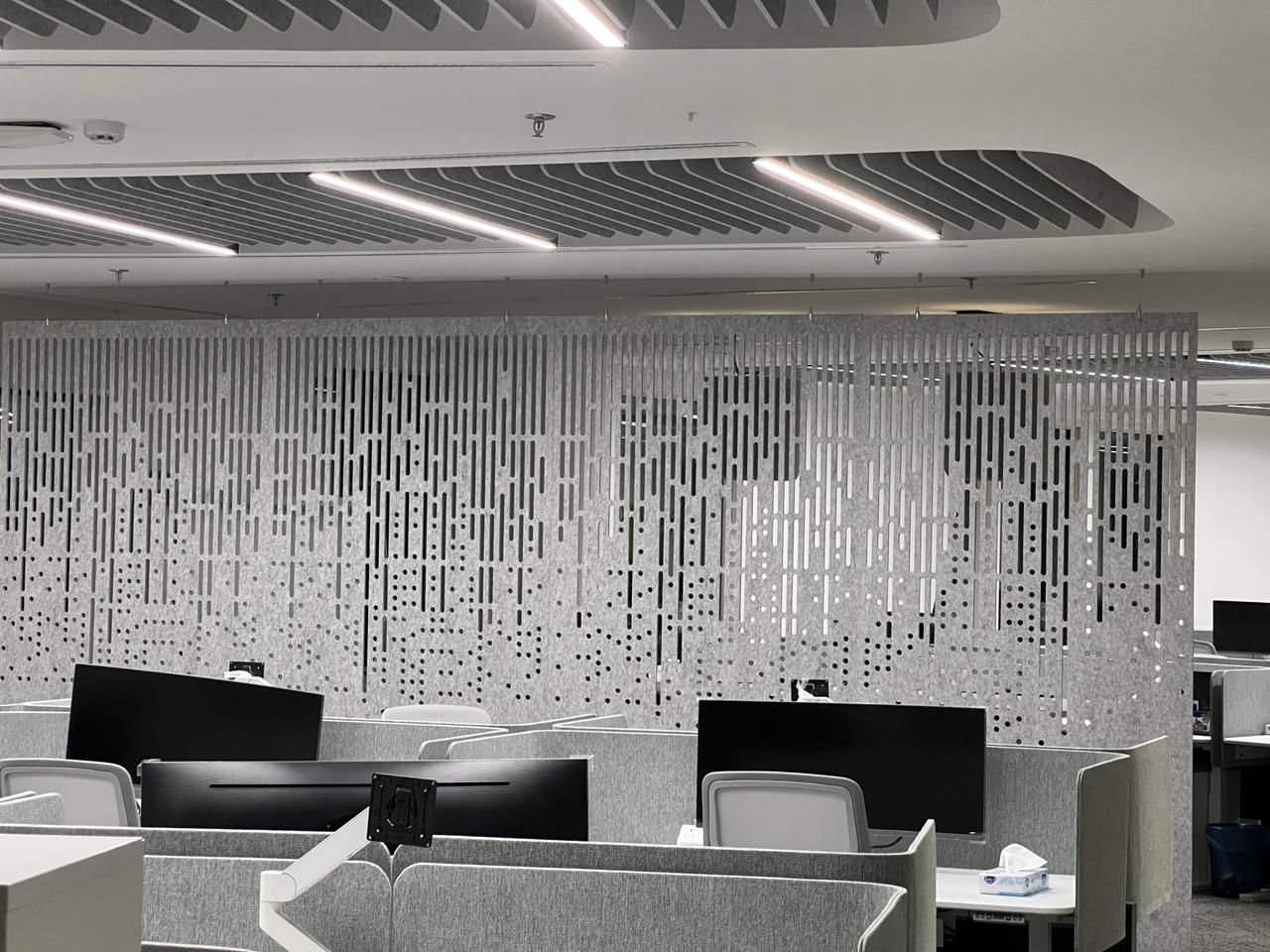 Hanging Decrasound acoustic screen with geometric cut-out design installed in an open-plan office.