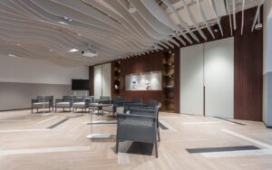 Curved wave-shaped acoustic baffles suspended from a ceiling to control reverberation in open spaces.