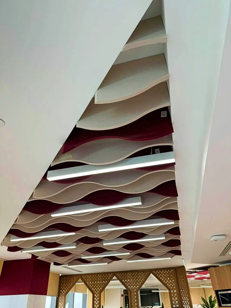 Sontext Wave acoustic ceiling baffles in alternating maroon and beige tones, designed to reduce echo and create a dynamic ceiling effect.