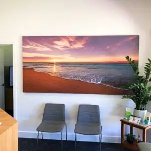 Serenity Acoustic Art Panel featuring a beach sunset photograph, installed in a modern office reception area to provide acoustic comfort and visual appeal.